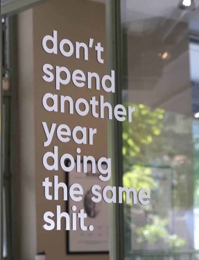 Window sign with bold white text: don't spend another year doing the same shit.